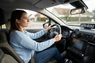 Jeune femme concentrée au volant d'une voiture d'auto-école lors de sa première leçon de conduite