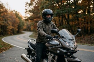 Motard équipé sur une moto de loisir garée sur une route forestière en automne, illustrant l'assurance moto de loisir