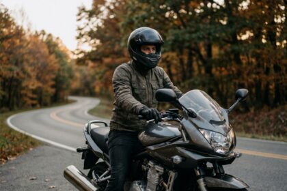 Motard équipé sur une moto de loisir garée sur une route forestière en automne, illustrant l'assurance moto de loisir